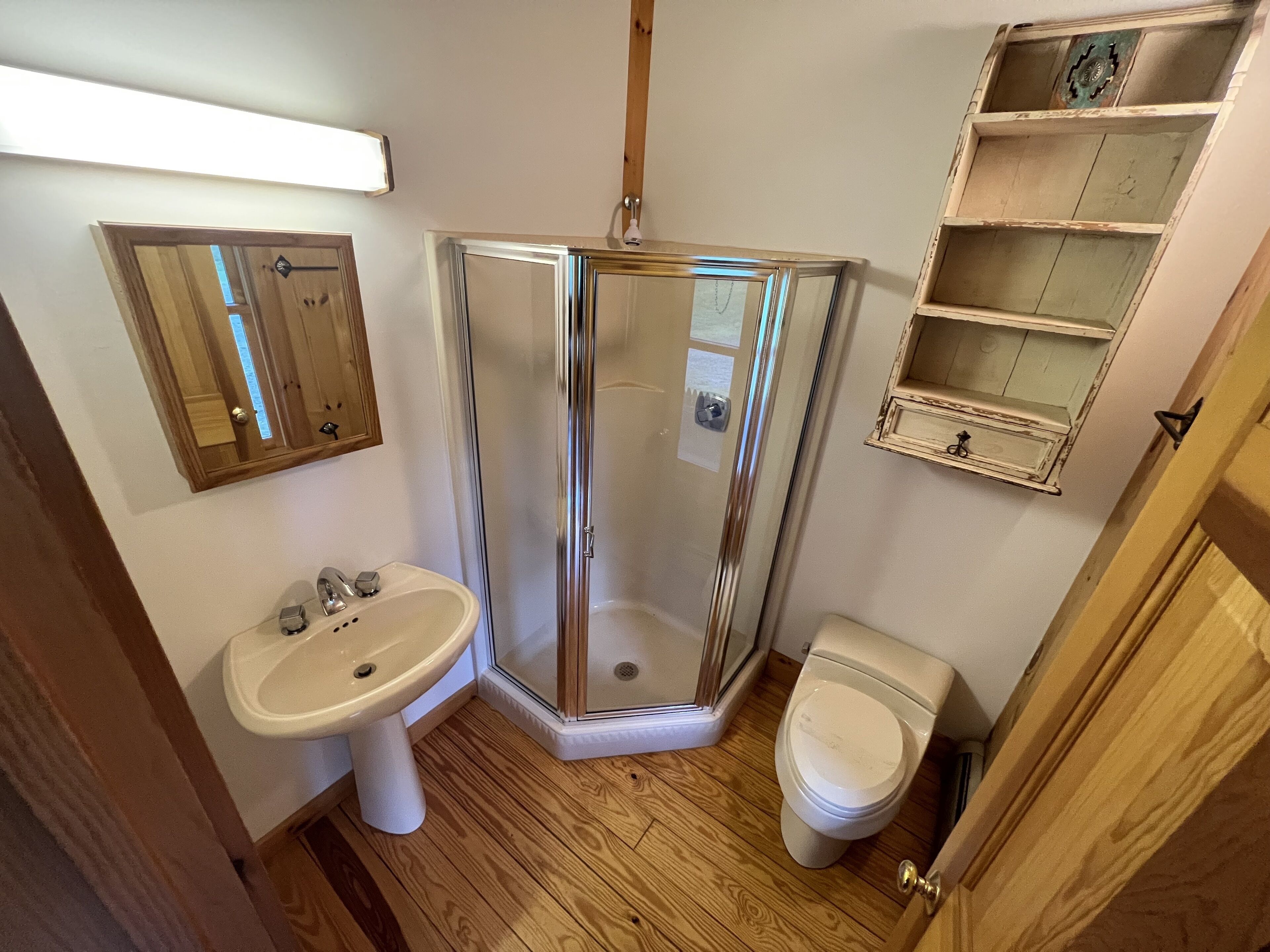 A bathroom with a glass shower enclosure, a sink, and a toilet.