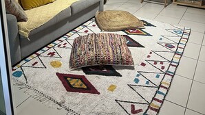 A living room with a sofa, a floor lamp, a chair, and a patterned rug.