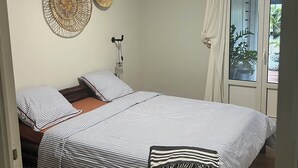 A bedroom with two beds, a ceiling fan, and a window with curtains.