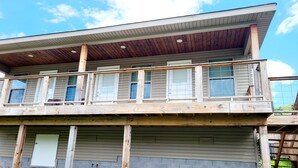 Un edificio a due piani con una terrazza in legno e numerose finestre.