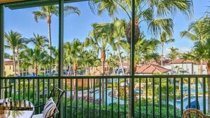 A balcony with a view of a pool and palm trees. - Luxury Residence 3BR near 5th Ave & Beach (Naples)