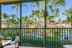 A balcony with a view of a pool and palm trees.