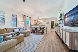 A modern living room with a sofa, dining area, and kitchen. - Luxury Residence 3BR near 5th Ave & Beach (Naples)