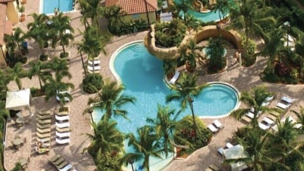 A resort with multiple swimming pools, palm trees, and lounge chairs. - Luxury Residence 3BR near 5th Ave & Beach (Naples)