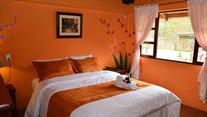 Ein Hotelzimmer mit einer orangefarbenen Wand, einem Bett mit weißer und brauner Bettwäsche, einem gerahmten Bild an der Wand und einem Vorhangfenster.