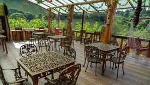 Eine Terrasse im Freien mit aufwendigen Metallmöbeln und Blick auf ein üppiges Tal.