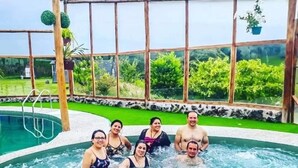 Eine Gruppe Menschen in einer Hottub-Anlage mit Glasabdeckung und einem Pool im Hintergrund.