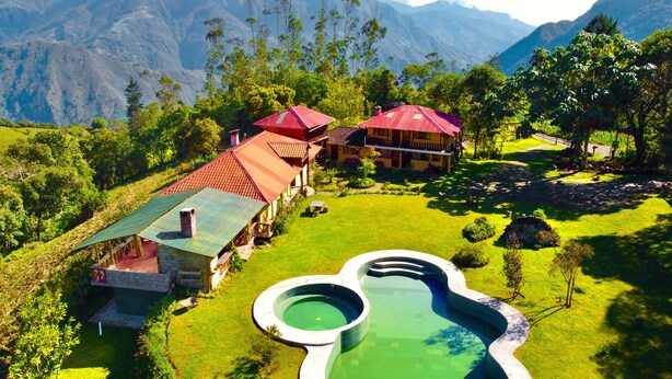 Ein Resort mit mehreren Gebäuden, einem Schwimmbad und üppiger Vegetation.