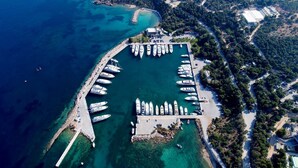 An aerial view of a marina with multiple boats docked, surrounded by a coastal landscape with trees and buildings. - VILLA HERMES/ Seaview / 7 min from the beach! (Vouliagmeni)