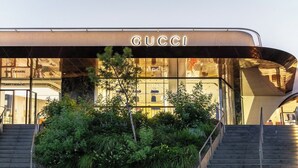A modern building with a prominent 'GUCCI' sign, featuring a glass facade and a landscaped area with stairs leading to the entrance. - VILLA HERMES/ Seaview / 7 min from the beach! (Vouliagmeni)
