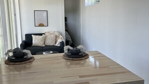 Een moderne keuken met een houten aanrecht, een wit inbouwkast en uitzicht op de woonkamer met een bank en een ingelijst beeld aan de muur.