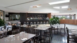 A modern restaurant with high ceilings, a bar area, and large windows providing natural light. - Sun City - Q Stay (Surfers Paradise)