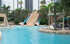 Una piscina con tobogán y palmeras.
