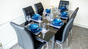 A dining table set with blue bowls, plates, and wine glasses, surrounded by black chairs.
