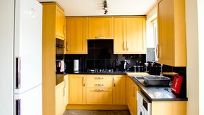A kitchen with wooden cabinets, a black countertop, and a stainless steel sink.