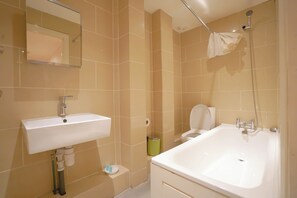 Enjoy a refreshing soak in the large bathtub with handheld showerhead, paired with a convenient sink and mirror.