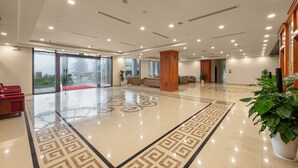 A spacious lobby with a polished floor, a central wooden pillar, and a red carpet leading to the exit. - Convention Center Sapa Hotel (Sa Pa)