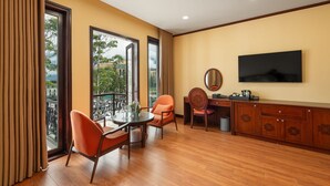 A hotel room with a balcony, a desk with a chair, a television, and a small table with chairs. - Convention Center Sapa Hotel (Sa Pa)
