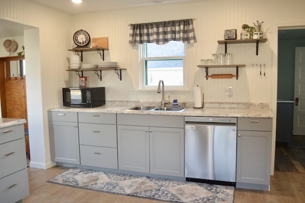 Fully equipped kitchen with microwave, blender, toaster and electric stove.