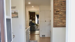 Un couloir doté d’un plancher en bois, d’une moquette bleu foncé et d’une porte donnant sur une pièce avec une fenêtre.