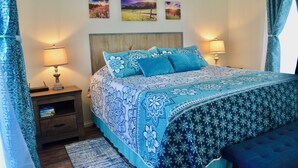 Une chambre à coucher comprenant un lit, deux lampes de chevet, une table de chevet, un tapis et trois œuvres d’art mural.