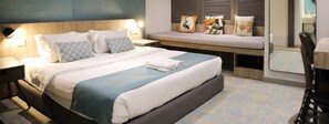 Habitación de hotel con cama, mesitas de noche, un banco y vistas al exterior.