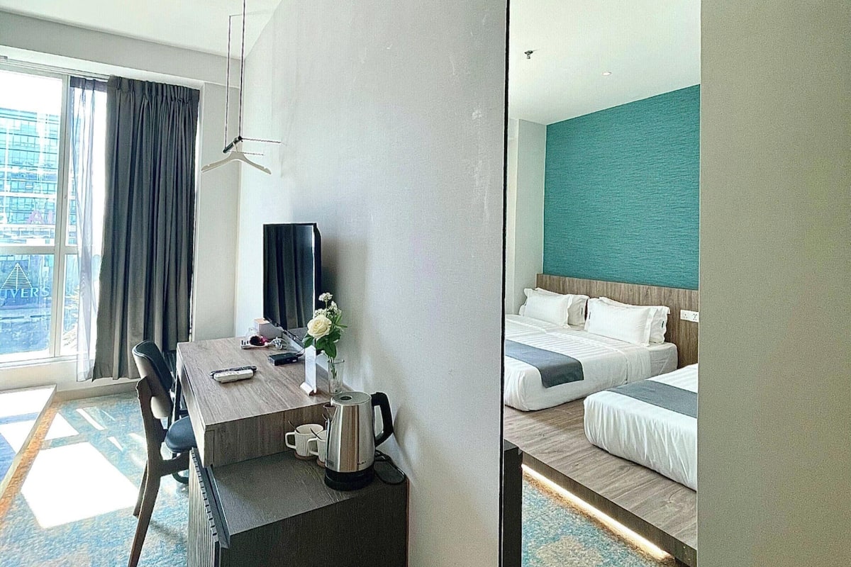 Een hotelkamer met een bureau, stoel, koffiezetapparaat en een bed met een blauwe accentmuur.
