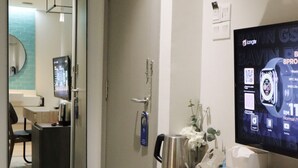 A hotel room with a wooden desk, a large mirror, a television, and a radiator. - Homi Breeze 和逸微风 (Kota Kinabalu)