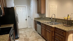A kitchen with granite countertops, wooden cabinets, a stainless steel sink, and a black refrigerator. - Elegant Mountain Townhome in Banner Elk (Banner Elk)