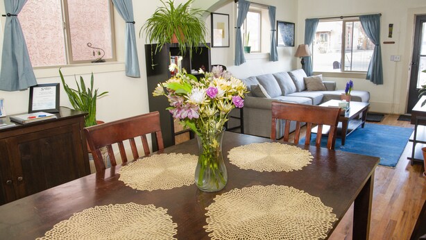 Een eethoek met een houten tafel, stoelen en een vaas met bloemen.