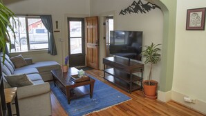 Een woonkamer met een bank, televisie, salontafel en een potplant.