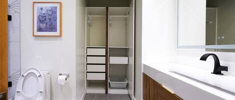 Un baño moderno con inodoro, lavabo y zona de ducha.