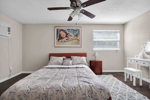 A bedroom with a bed, a ceiling fan, a poster on the wall, a bedside table, a lamp, and a window with blinds. - Smart Saver Townhouse, Family Friendly, Close to NAS Jax, Long-Term, Washer and Dryer (Jacksonville)