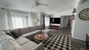 A modern living room with a sectional sofa, a coffee table, and a checkered rug.