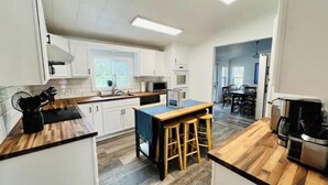 A modern kitchen with white cabinets, a wooden countertop, and a central island with stools.