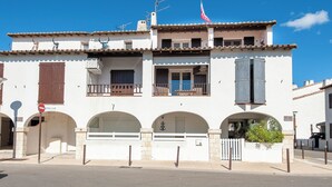 Un immeuble de deux étages avec une façade blanche, de nombreux balcons et un drapeau.