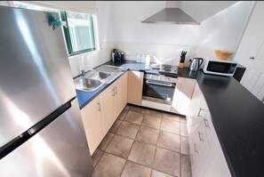 A modern kitchen with stainless steel appliances, a sink, and a window. - 4 bedroom, 4 bathroom lakefront home. (Meningie)