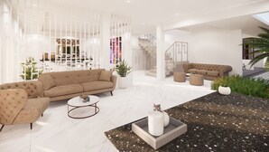 A spacious living area with a large beige sofa, a round coffee table, and a small side table with decorative items. There is a staircase leading to an upper level, and a potted plant is visible in the foreground.