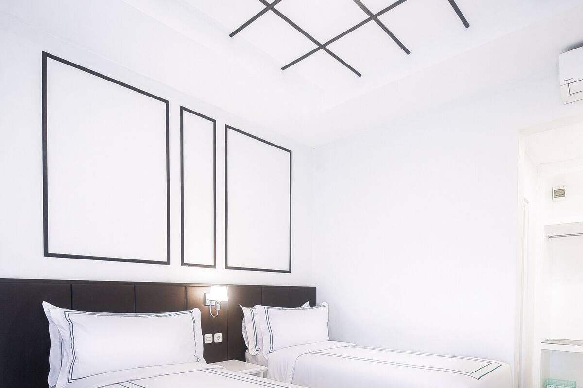 A hotel room with two beds, a modern ceiling design, and a marble floor.