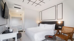 A modern hotel room with a bed, a desk, a chair, and a TV.