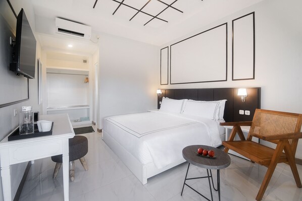A modern hotel room with a bed, a desk, a chair, and a TV. - Hotel Noola Malioboro (Yogyakarta)