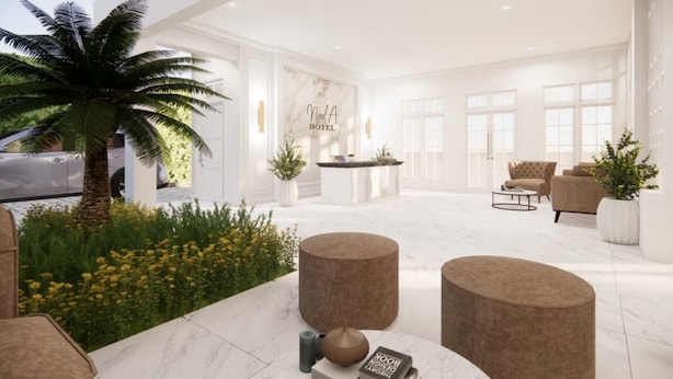 A spacious hotel lobby with a palm tree, a reception desk, and a seating area with modern furniture.