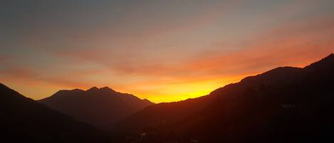 A mountainous landscape during sunset with silhouettes of mountains and a valley.