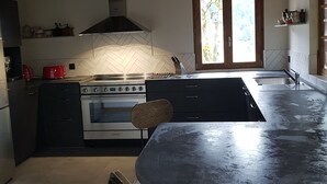 Eine moderne Küche mit einer großen Kochinsel, Holzboden und Blick durch ein Fenster.