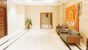 A hotel lobby with a marble floor, a chandelier, a reception desk, and a sofa. - Tongxilai Hotel (Jingyan)