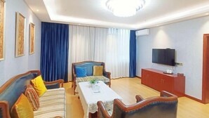 A living room with a sofa, a table, a TV, and a cabinet. - Tongxilai Hotel (Jingyan)