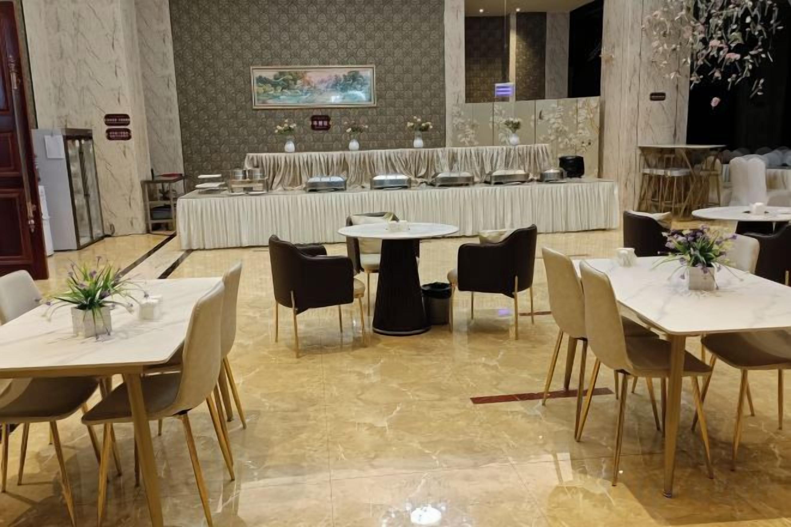 A hotel dining area with round tables, chairs, and a buffet setup.