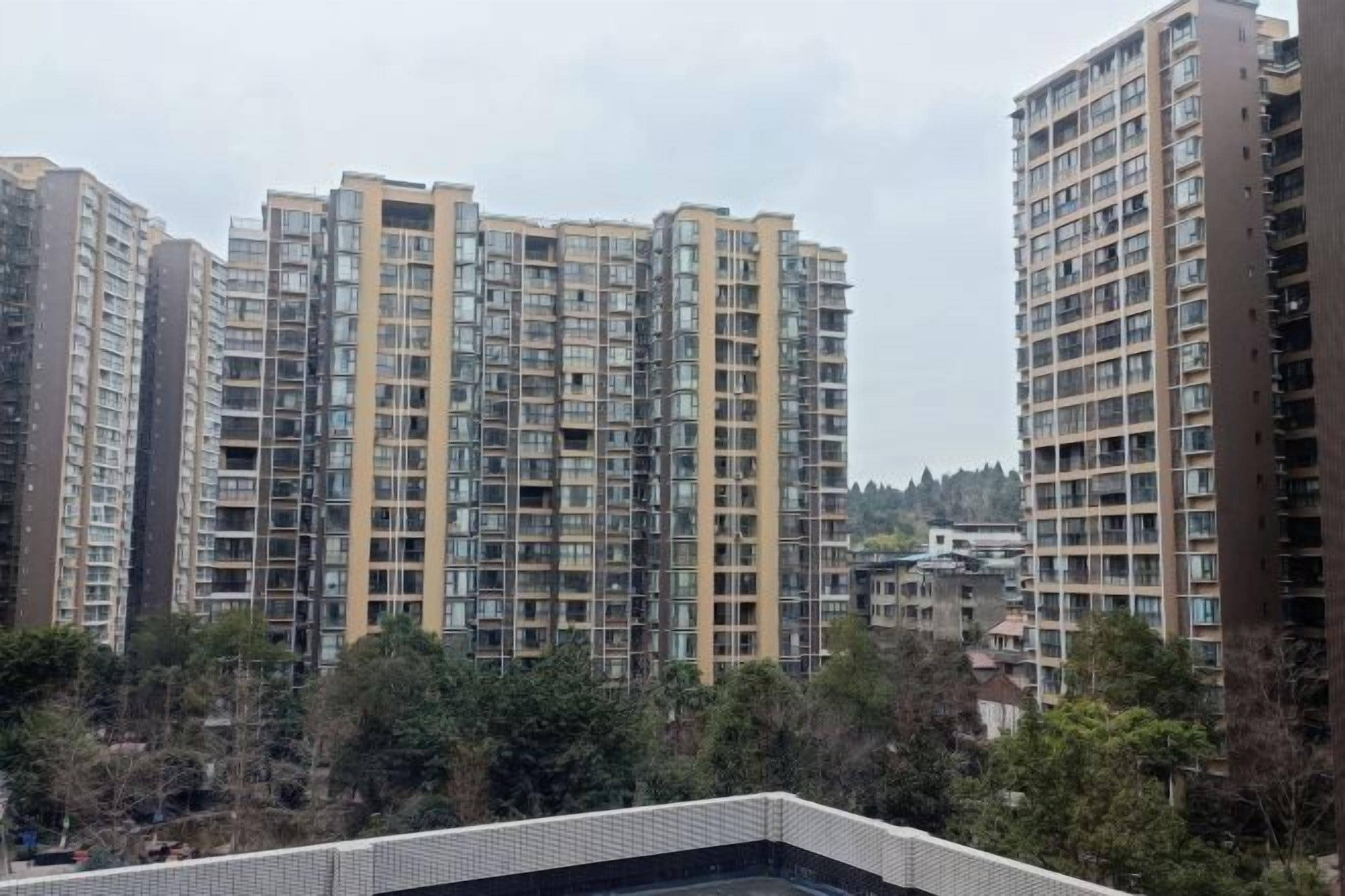 Un edificio residencial alto con varios balcones y una terraza con tejas.