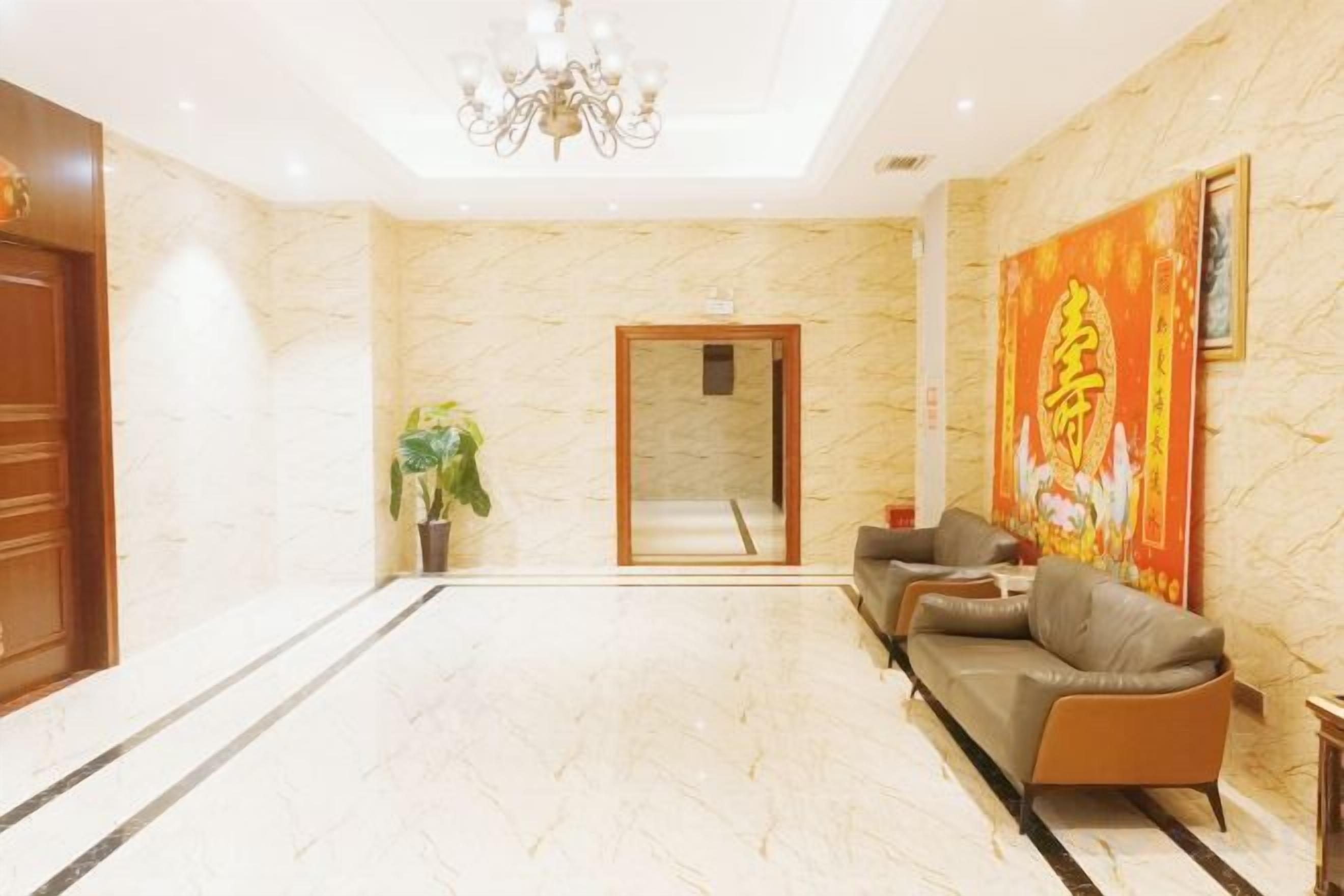 Un hall de hotel con piso de mármol, un sofá, una planta en maceta y una araña.