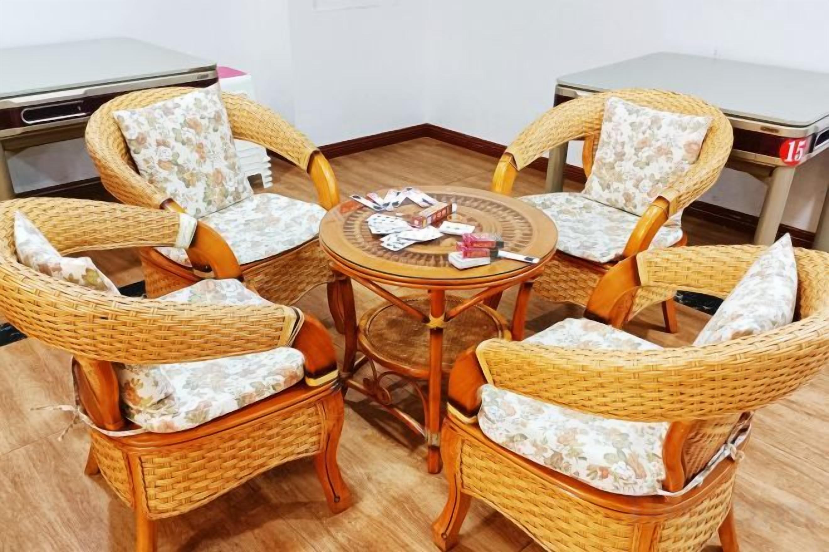 A round table with four wicker chairs, each with a cushion.